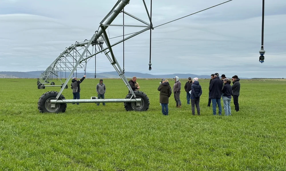 a group of people in a paddock learning about center pivots