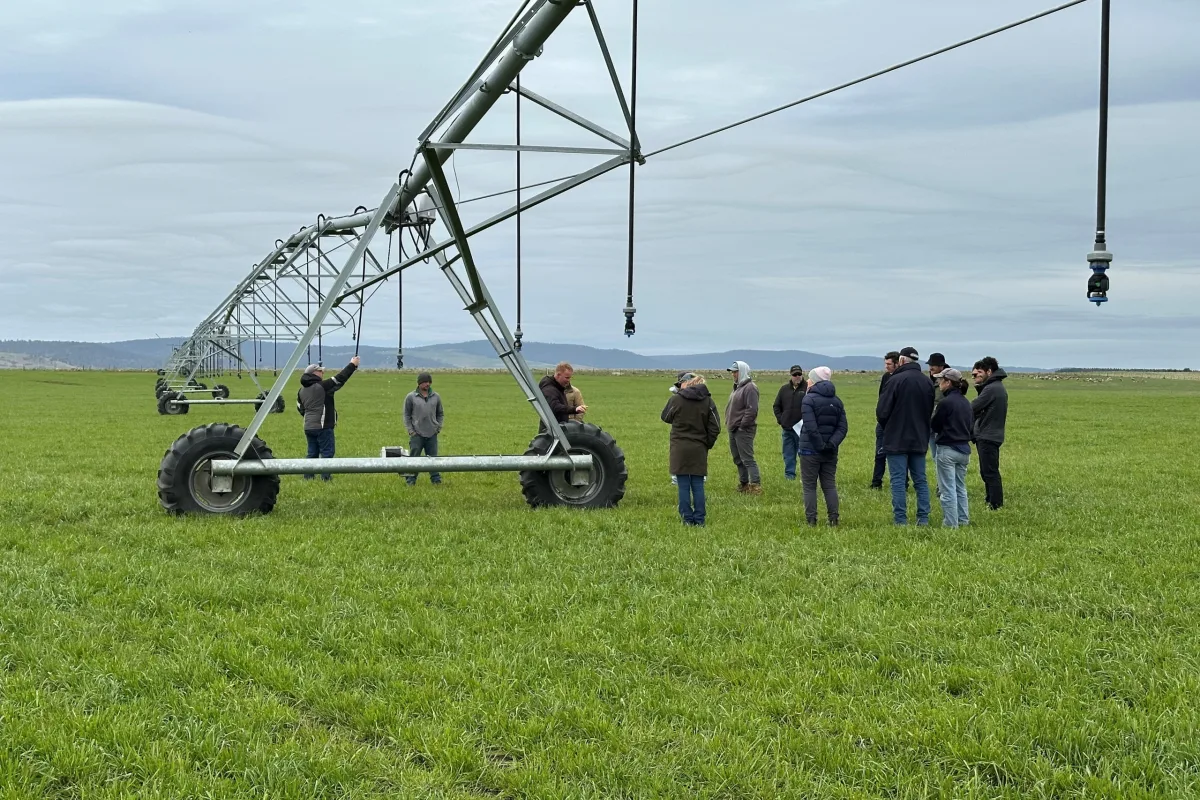 a group of people in a paddock learning about center pivots